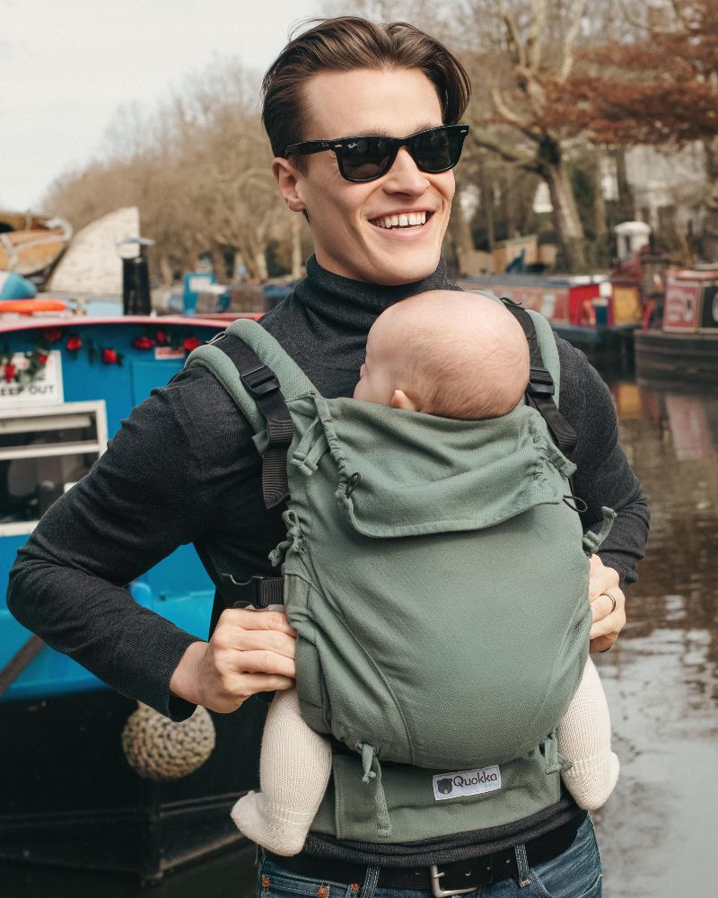 PADRE PORTEANDO A SU BEBÉ EN LA MOCHILA ERGONOMICA QUOKKABABY E CARRIER CON DETALLE DEL TEJIDO DE FULAR